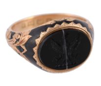 An 18 carat gold onyx signet ring,   the oval banded onyx carved with a crest, between foliate
