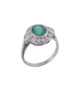 An emerald and diamond ring,   the central oval shaped emerald collet set within a surround of