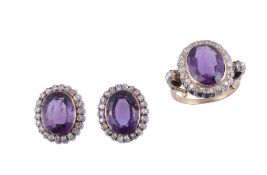 An amethyst and diamond ring,   the central oval shaped amethyst collet set within a surround of