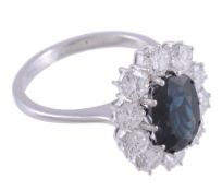 A sapphire and diamond cluster ring,   the central oval shaped sapphire claw set within a surround