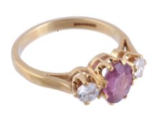 A pink sapphire and diamond ring,   the central oval shaped pink sapphire claw set between two