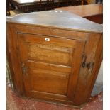 A 19th Century elm hanging corner cupboard with fielded panelled door enclosing shaped shelves
