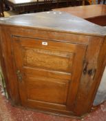 A 19th Century elm hanging corner cupboard with fielded panelled door enclosing shaped shelves
