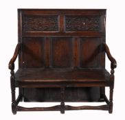 An oak hall bench, early 18th century and later, with carved and panelled back on downswept arms,
