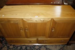 An Ercol elm sideboard with three cupboards and two drawers below 130cm wide