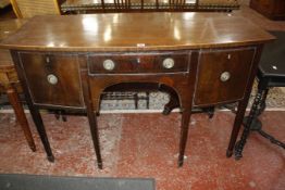 A George III style mahogany bowfront sideboard with a central drawer flanked by a cupboard and