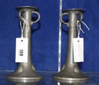 A pair of pewter candlesticks in the Arts and Crafts style, each with triple ring handles above