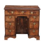 A George II walnut kneehole desk  , circa 1735, the quarter veneered and crossbanded top above a