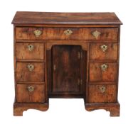 A George II walnut kneehole desk  , circa 1735, the quarter veneered and crossbanded top above a