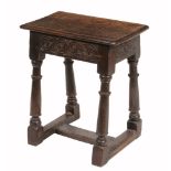A Charles II oak joint stool  , circa 1660, the seat with moulded edge above a freize with scroll