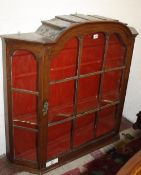 A glazed wall hanging display cabinet with arched central section and canted angles 96cm high, 110cm