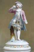 A 20th Century porcelain figure of a man in a pink frock coat (damaged), 18cm high