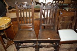 A pair of high back Jacobean oak chairs with solid seats and ring turned legs joined by stretchers