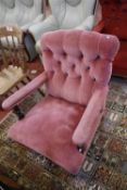 A pair of Victorian armchairs, with button upholstered back and open arms on turned legs - in
