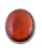 An amber and half pearl brooch, the oval cabochon amber within a border of...  An amber and half