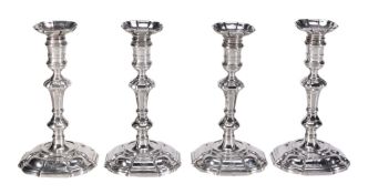 A set of four early George II cast silver shaped square candlesticks by...  A set of four early