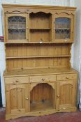A pine dresser   with leaded glazed cabinets to the upper section with drawers and cupboards to the