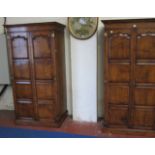 A pair of oak18th century style wardrobes   with panelled doors raised on a plinth base.97cm wide x