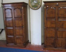 A pair of oak18th century style wardrobes   with panelled doors raised on a plinth base.97cm wide x