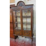 An Edwardian china display cabinet   with raised decoration to the doors raised on slender turned