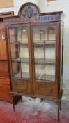 An Edwardian china display cabinet   with raised decoration to the doors raised on slender turned