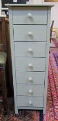 A tall narrow green painted chest of seven drawers  .126cm high.