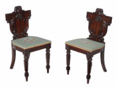 A pair of mahogany hall chairs,   circa 1835 and later, each shaped back carved with foliate