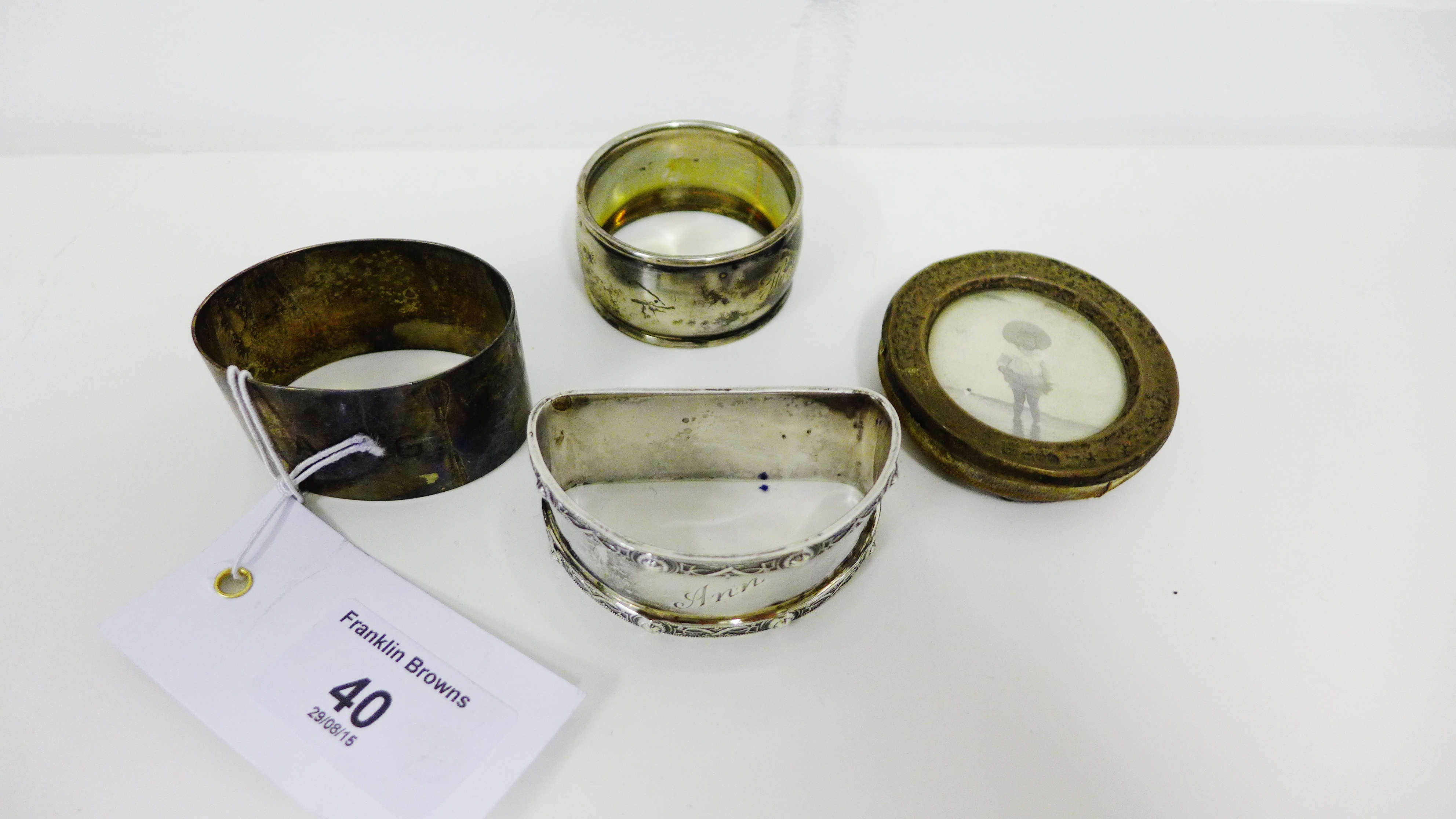 Three silver napkin rings and a small circular silver photograph frame, mixed hallmarks (4)