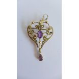 An early 20th century yellow metal open work amethyst and seed pearl pendant brooch with a pear