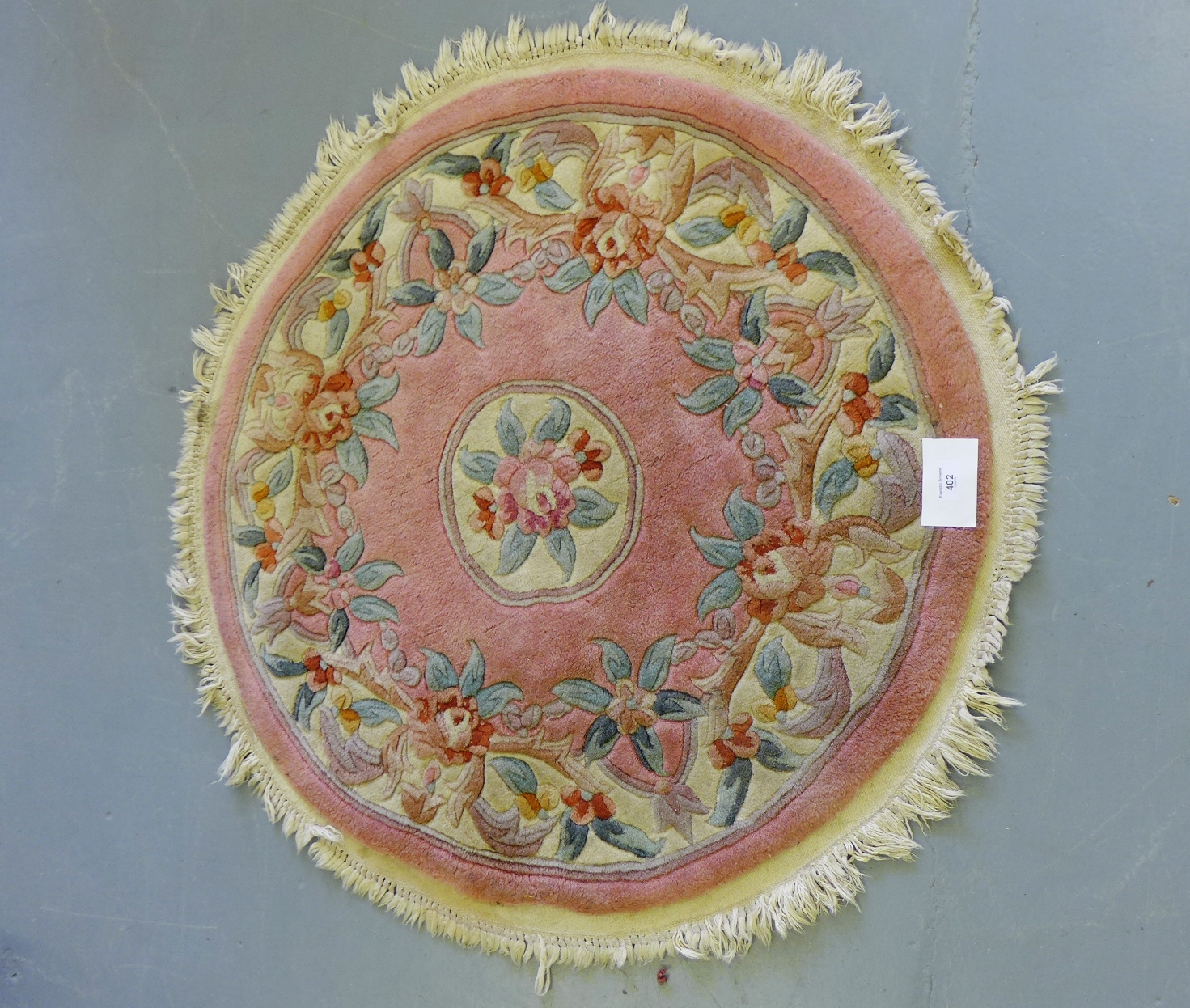 A circular Chinese wool rug with floral medallions to a rose field, 100cm