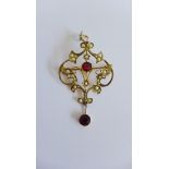 An Edwardian 9 carat gold open work ruby and seed pearl set pendant brooch with a circular bright