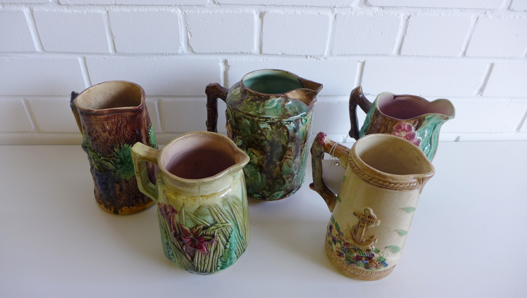 A group of five various 19th century shell, leaf and floral relief moulded majolica jugs (a/f) (5)