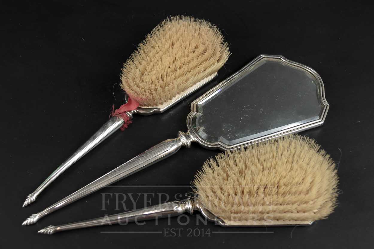 A three piece Art Deco dressing table set, comprising two brushes and a hand mirror, makers mark for