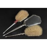 A three piece Art Deco dressing table set, comprising two brushes and a hand mirror, makers mark for