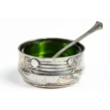 A Tudric pewter salt with original green glass liner, with conforming spoon with green glass