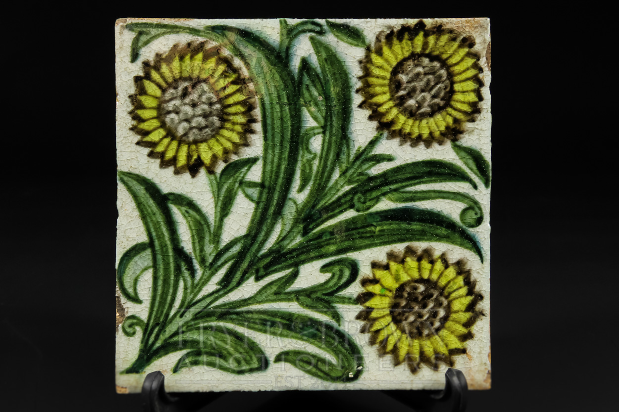 A William de Morgan Bedford Park tile, the pale grey ground decorated with three leafy sunflowers to