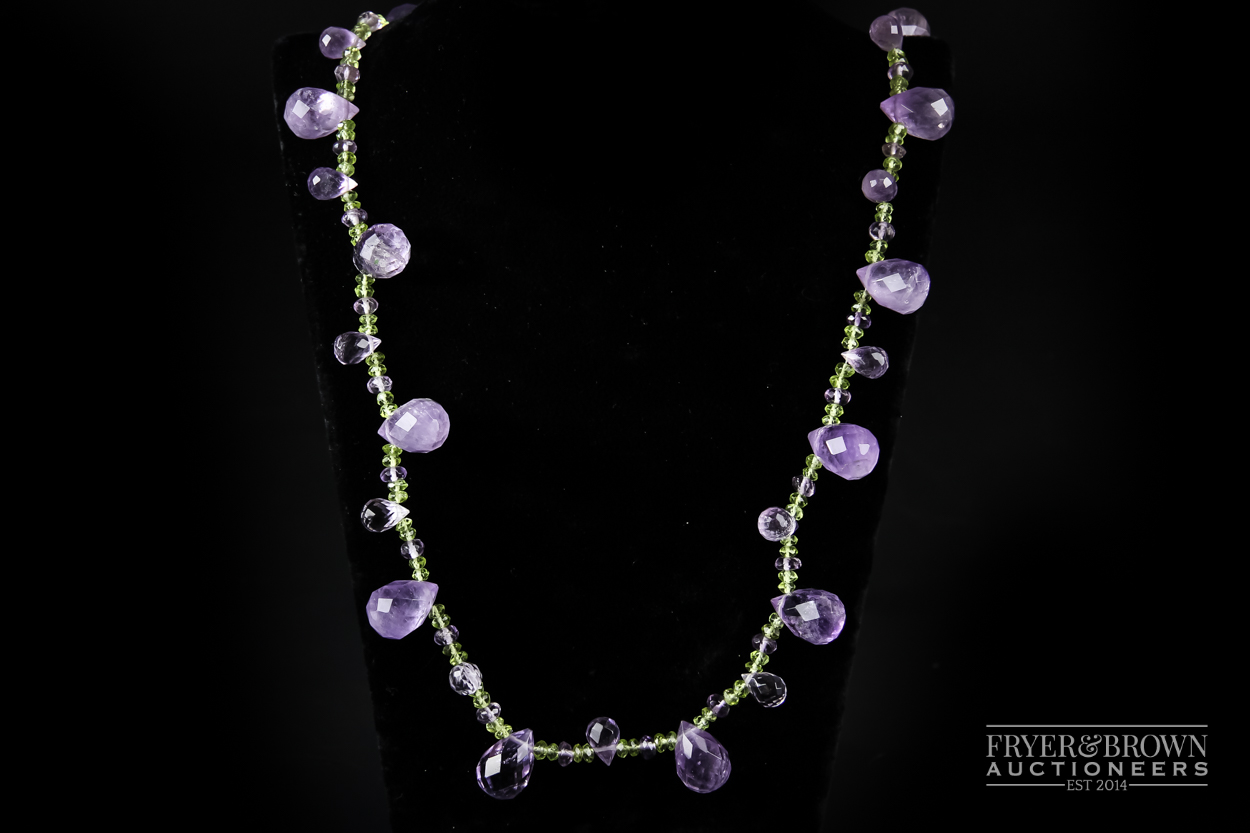 A briolette cut amethyst and faceted amethyst long chain with a textured silver heart shaped clasp