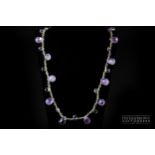 A briolette cut amethyst and faceted amethyst long chain with a textured silver heart shaped clasp