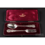 A Walker and Hall silver cased Christening set, spoon and fork, the handles cast with cherubs,