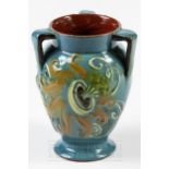 A C.H. Brannam Pottery three-handled vase, painted with a stylised flower on a blue ground, 11.5cm