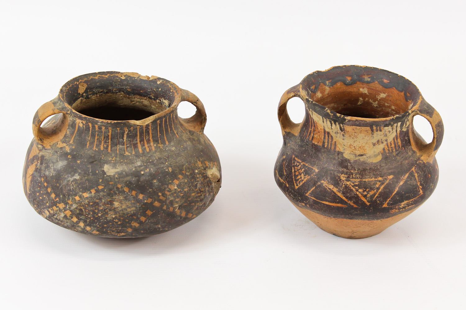 Two Chinese Neolithic redware pottery urns, each of squat globular form, with loop handles to the