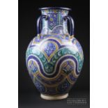 A Moroccan pottery four-handled urn, painted with a design of spandrels and shaped borders in