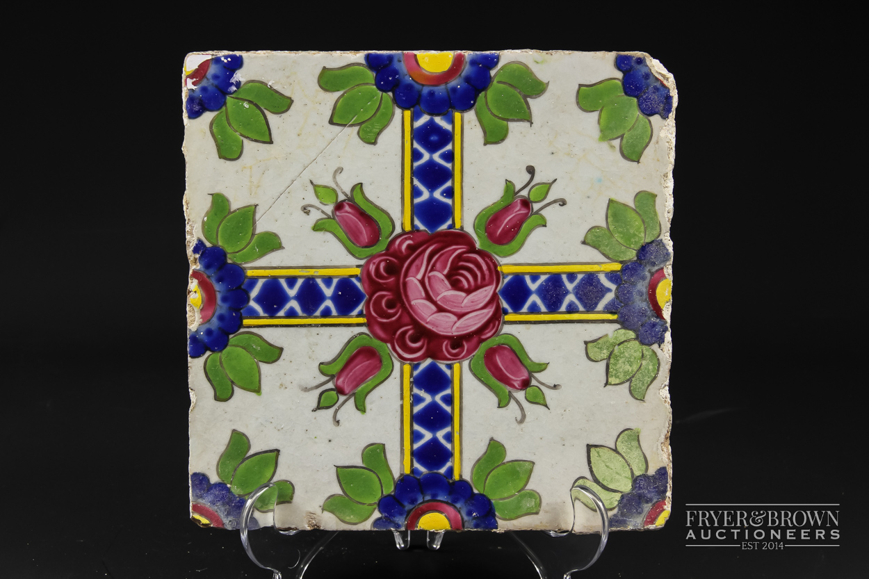 A Qajar tile, brightly glaze with a Damascus rose and four rose buds on crossed band, 19.5cm square