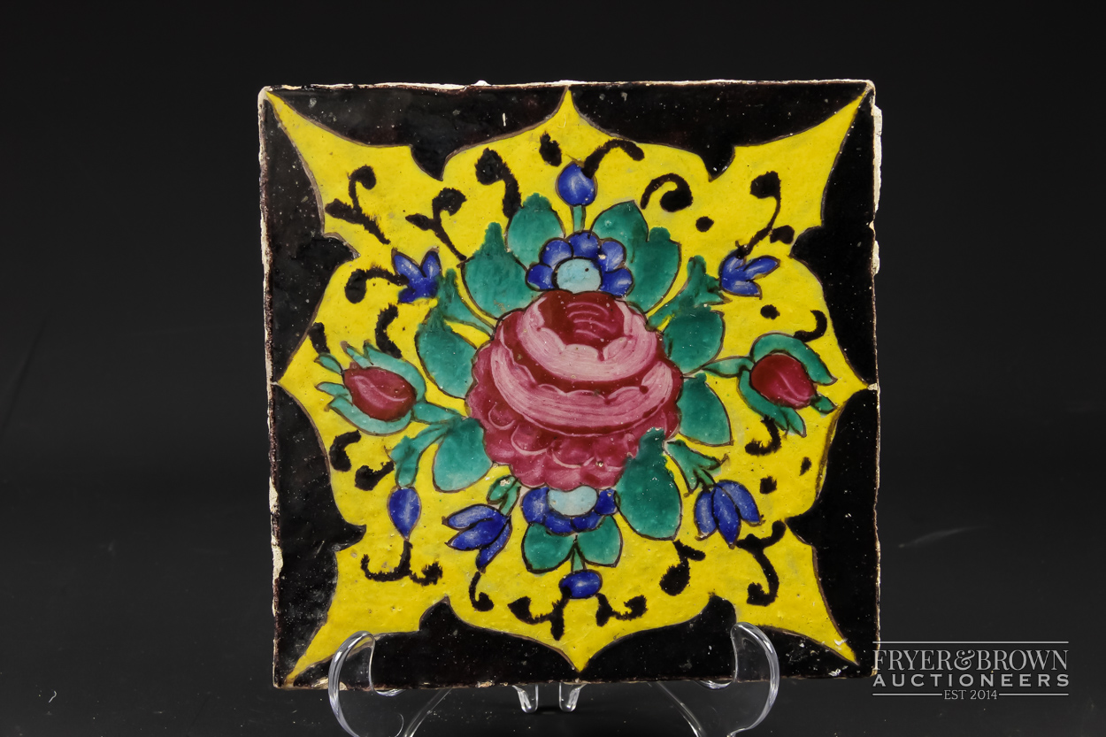 A Qajar tile, brightly glazed with a Damascus rose, two buds and blue flowers on a yellow reserve,