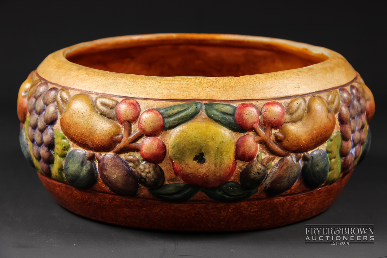 A Compton pottery bowl, decorated in high relief with a band of fruit, orange ground, impressed mark