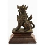 A Tibetan or Nepalese bronze figure of a crouching lion dog, probably late 19th century, heavily