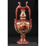 A Craven & Dunnill ruby lustre two handled vase, bottle form with stylised leaf handles, decorated