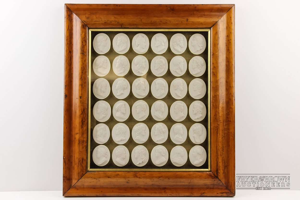 A large group of plaster seals, after the antique, mounted and framed in birdseye maple effect