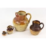 A group of four stoneware jugs, sprigged with topers and hunting scenes, including a miniature
