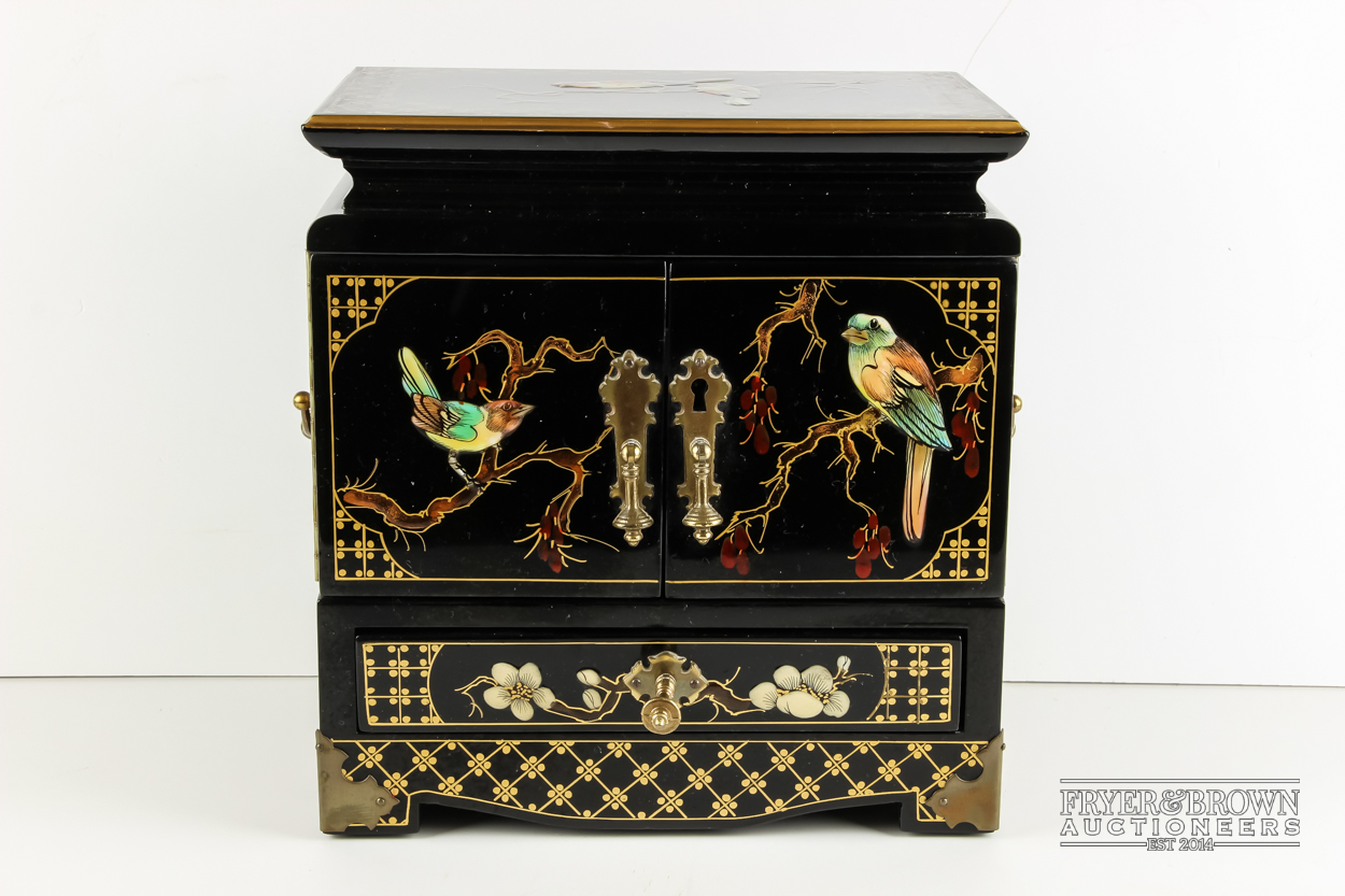 An Oriental style black lacquer jewellery box decorated with birds and flowers
